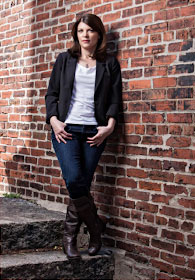 Melinda Leigh leaning against a brick wall